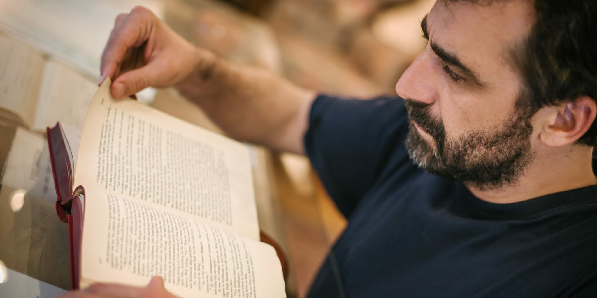 Curious man reading old book in his library at home. Retro style